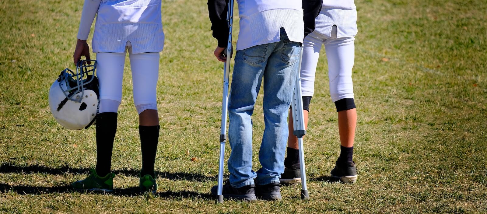 Injured football athlete standing wtih crutches