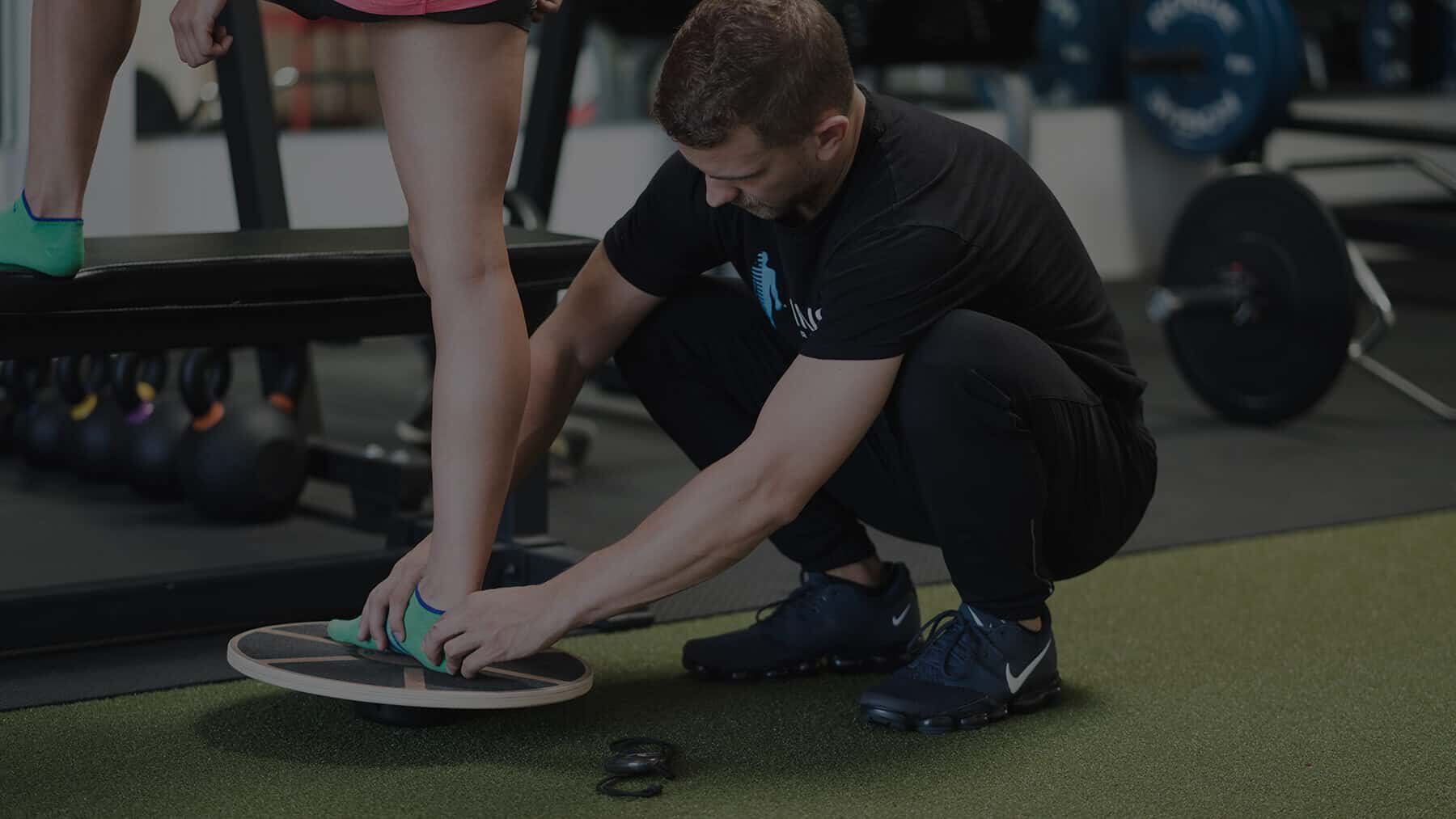 Trainer and athlete next to weightlifting equipment
